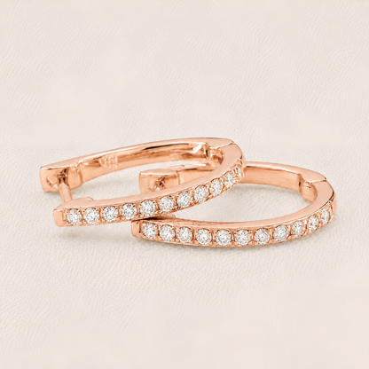 Rose gold hoop earrings with clear gemstones on a light beige background