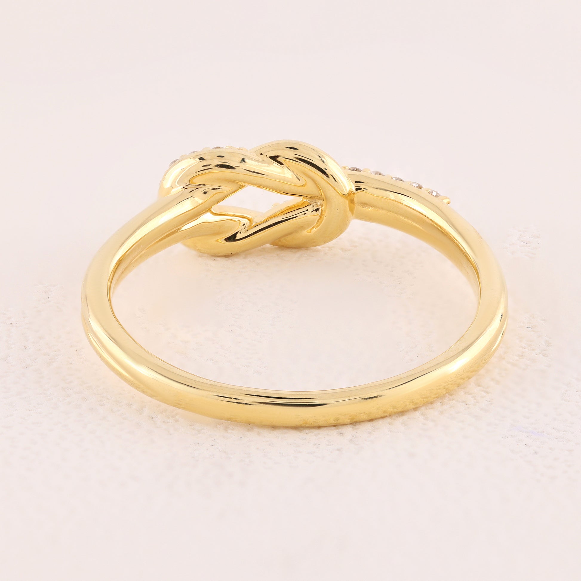 Gold knot ring on a light beige background