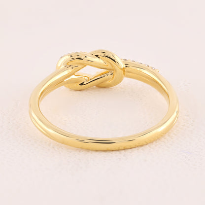Gold knot ring on a light beige background