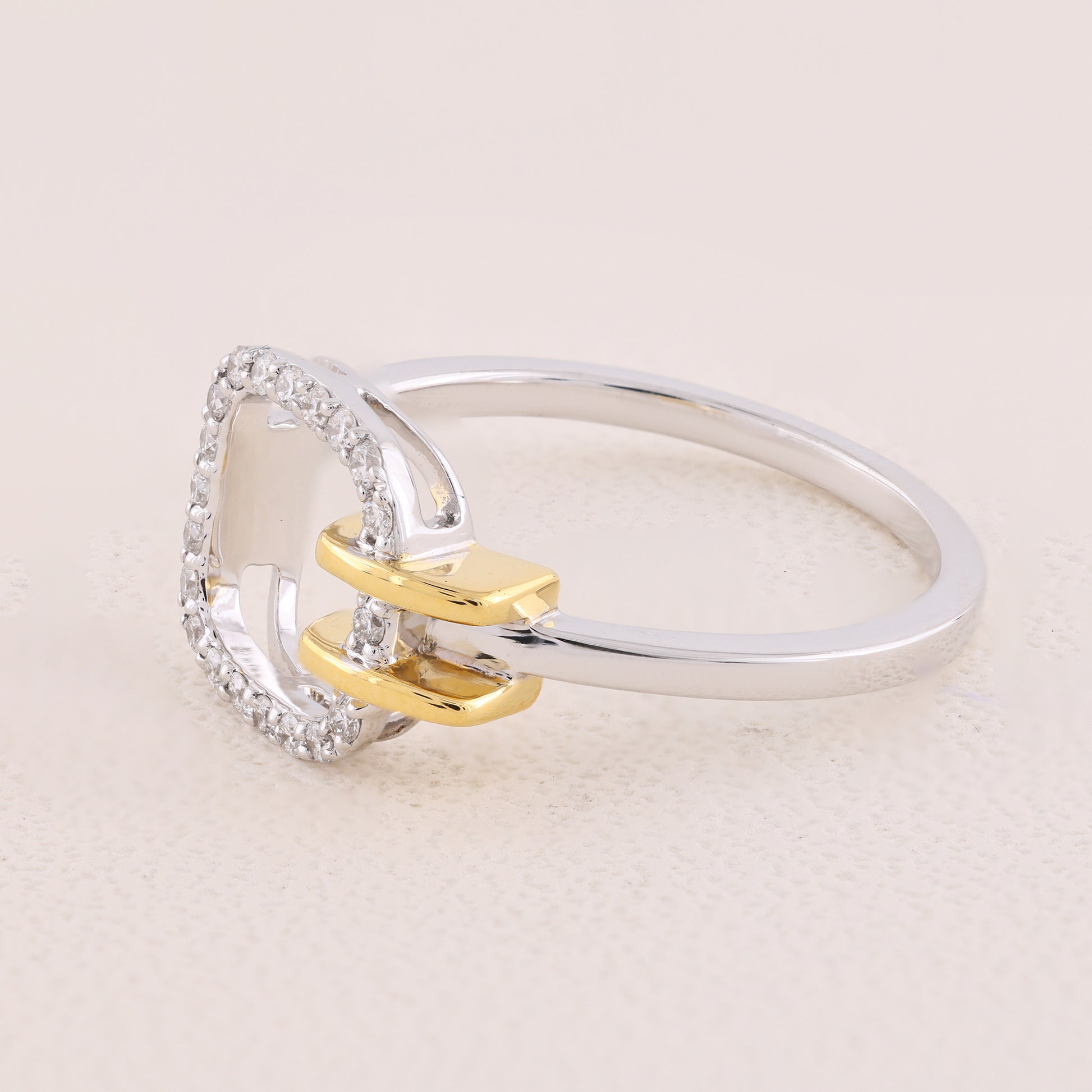 Silver and gold ring with diamond accents on a light beige background