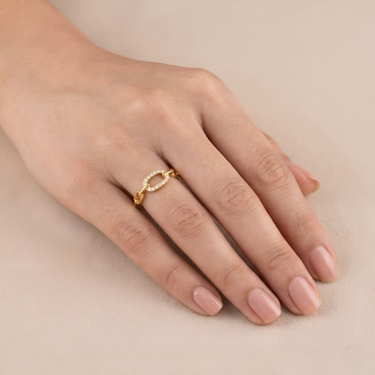 Hand wearing a gold ring with pearls on a beige background