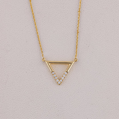 Gold necklace with a triangle pendant on a light gray background