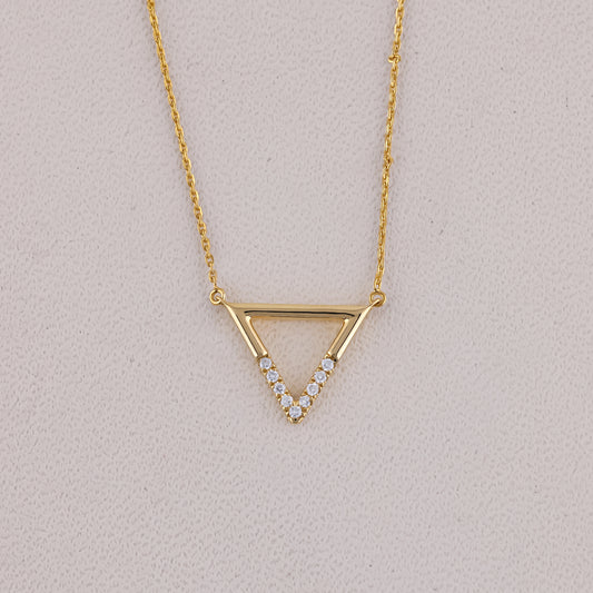 Gold necklace with a triangle pendant on a light gray background