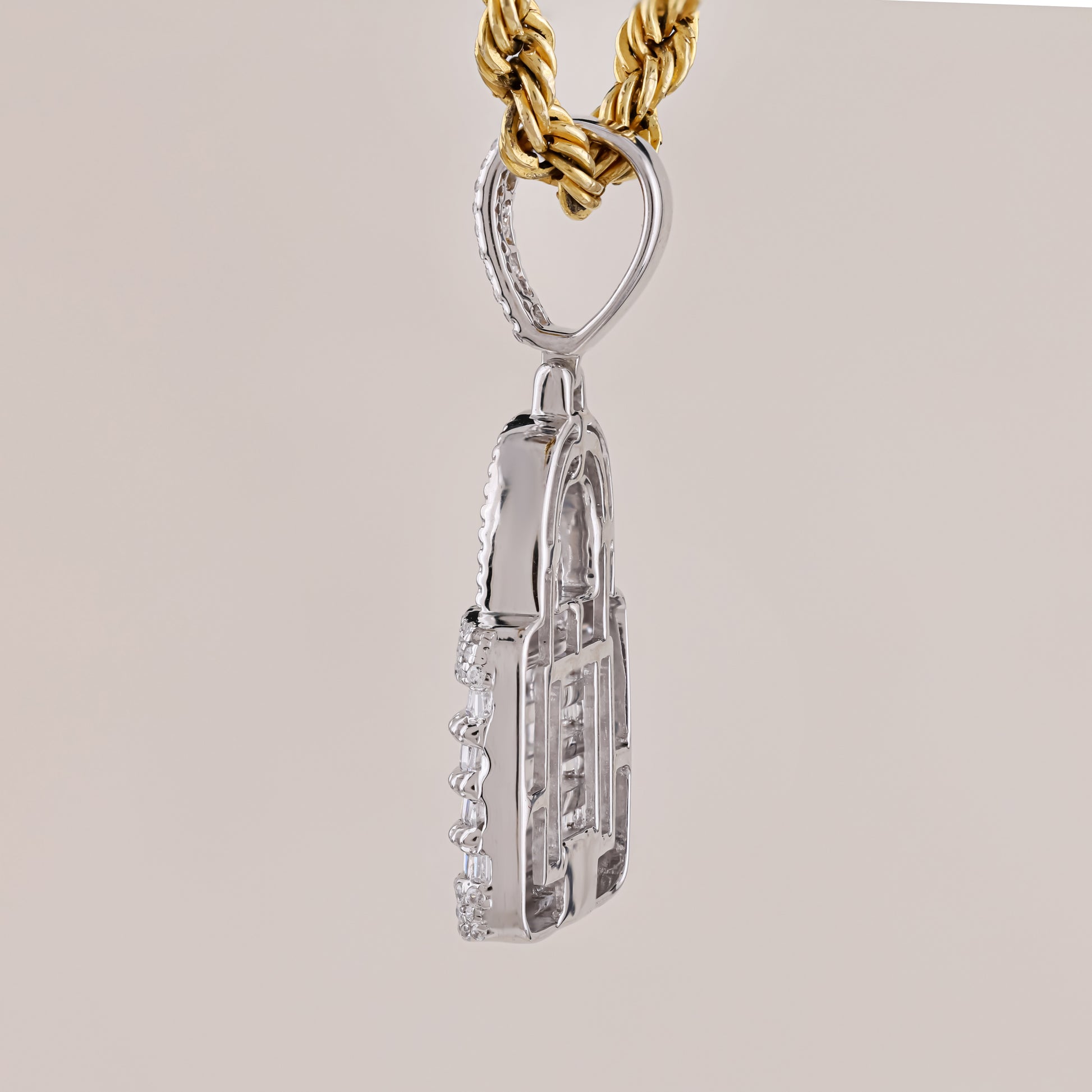 Silver pendant on a gold chain against a beige background