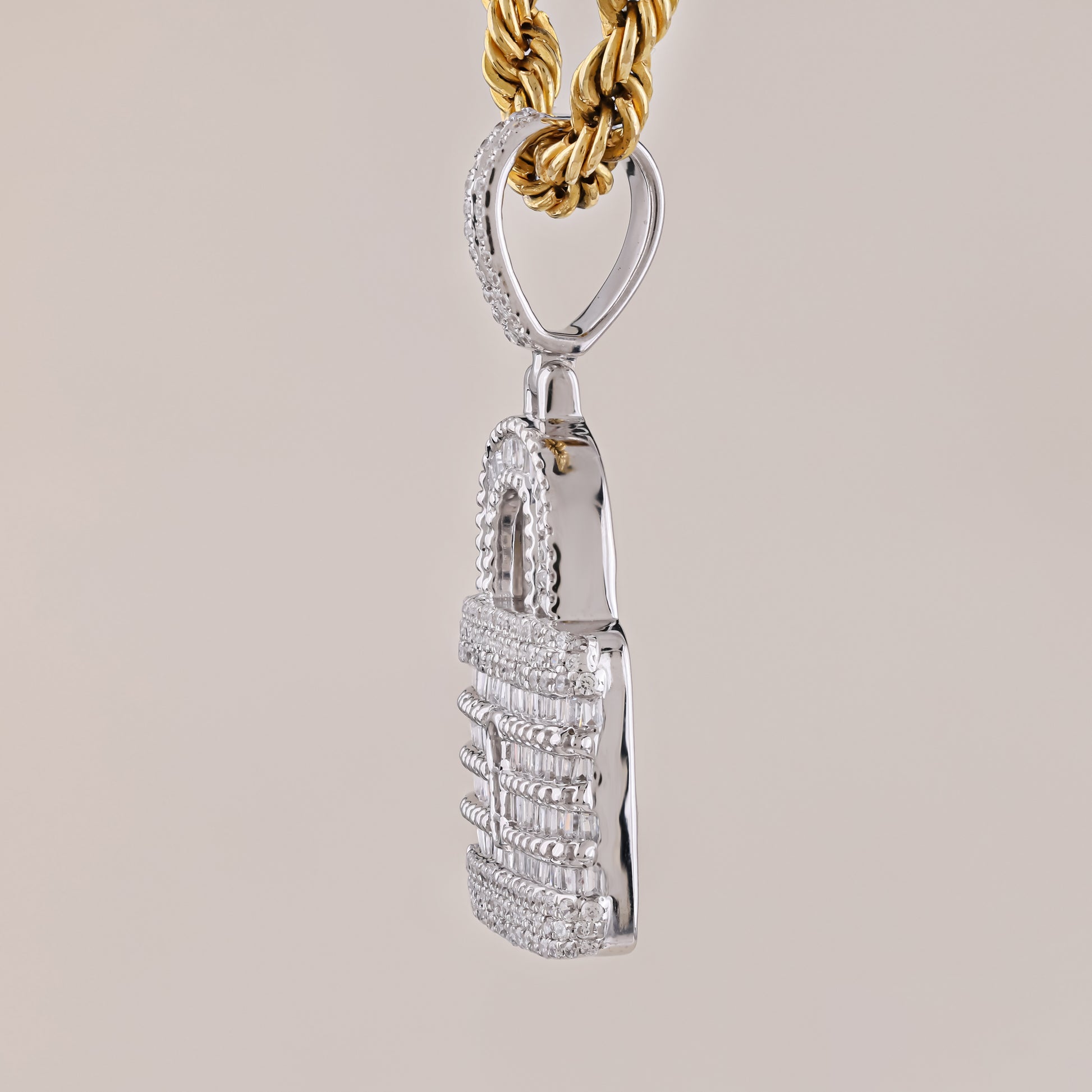 Silver pendant with intricate design on a gold chain against a beige background