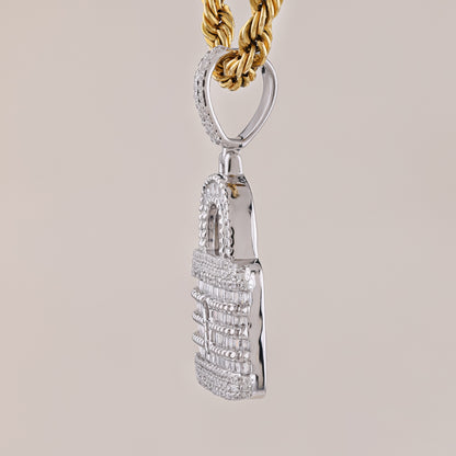 Silver pendant with intricate design on a gold chain against a beige background