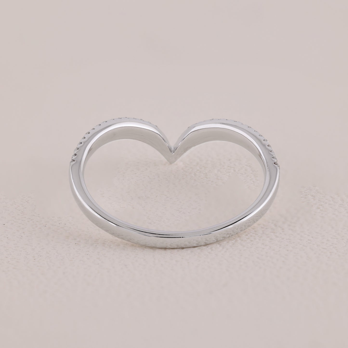 Silver heart-shaped ring on a beige background