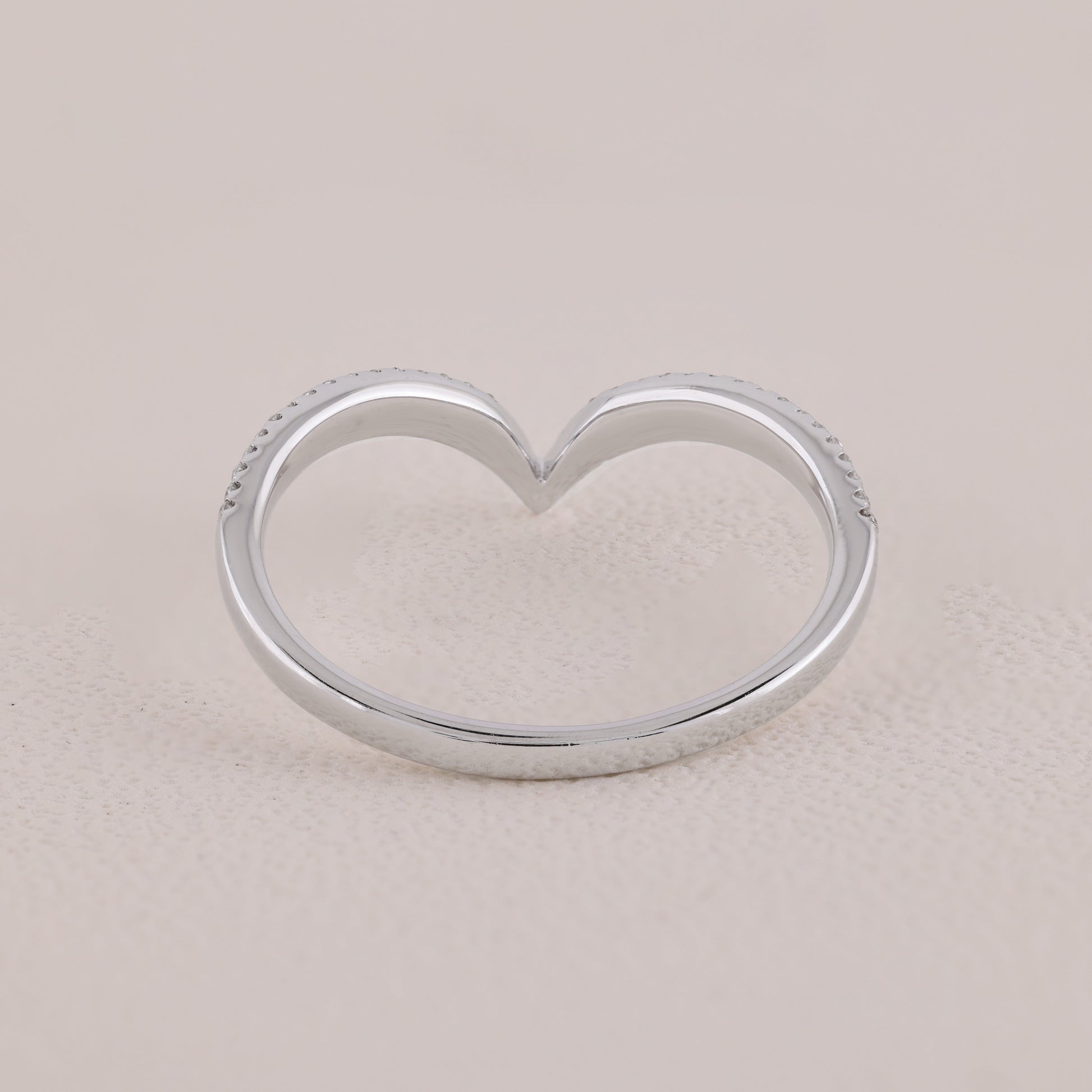 Silver heart-shaped ring on a beige background