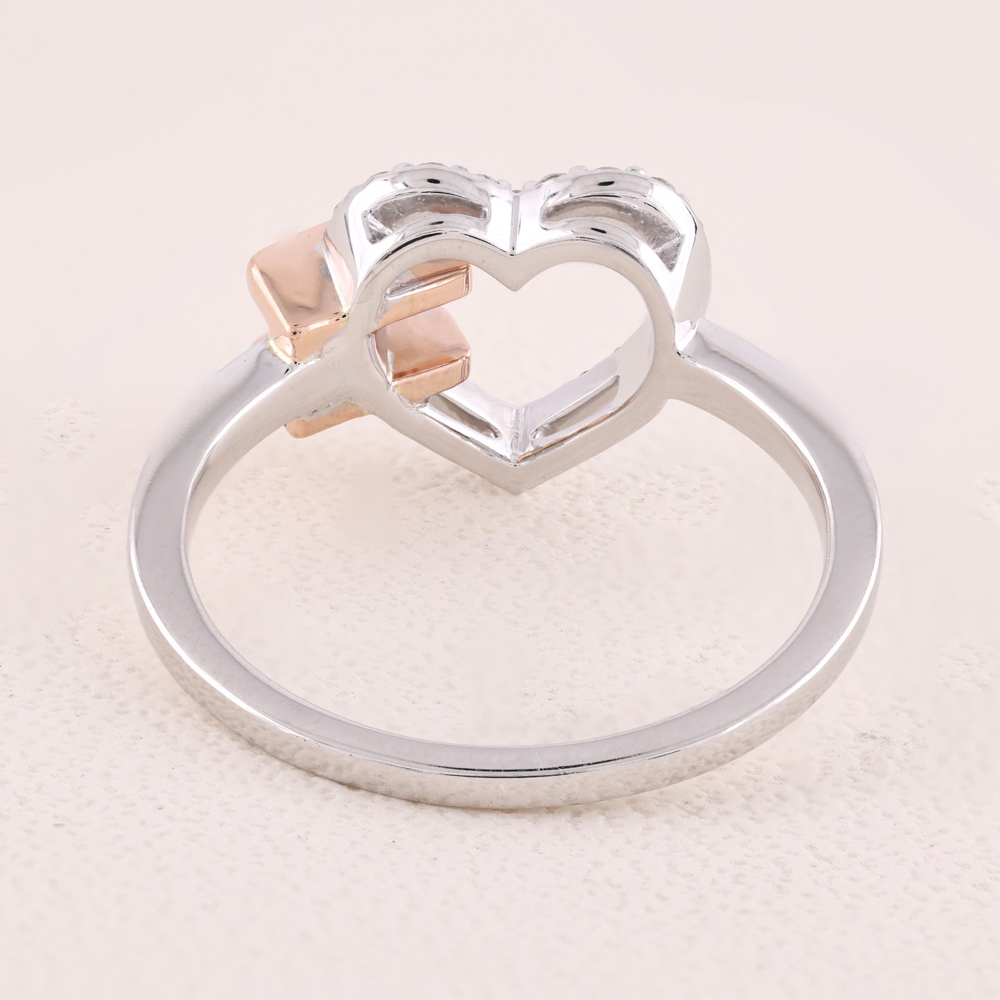 Silver ring with a heart design on a light beige background