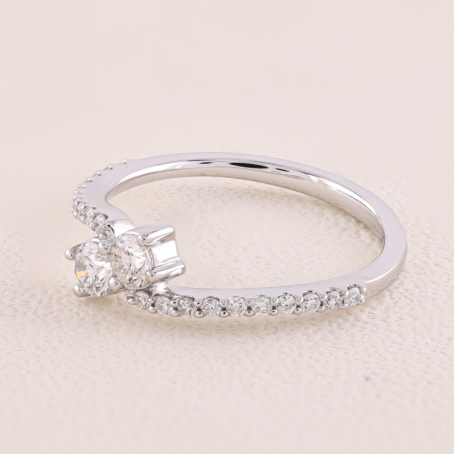 Silver ring with two diamonds on a beige background
