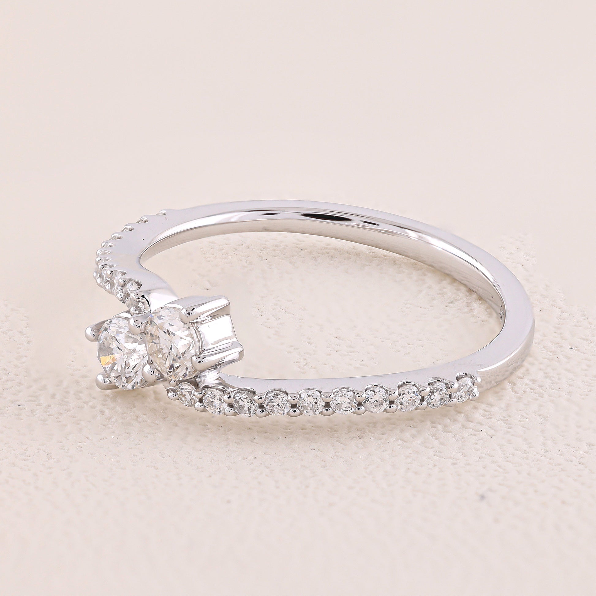 Silver ring with two diamonds on a beige background