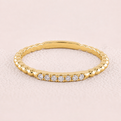 Gold ring with small diamonds on a light pink background