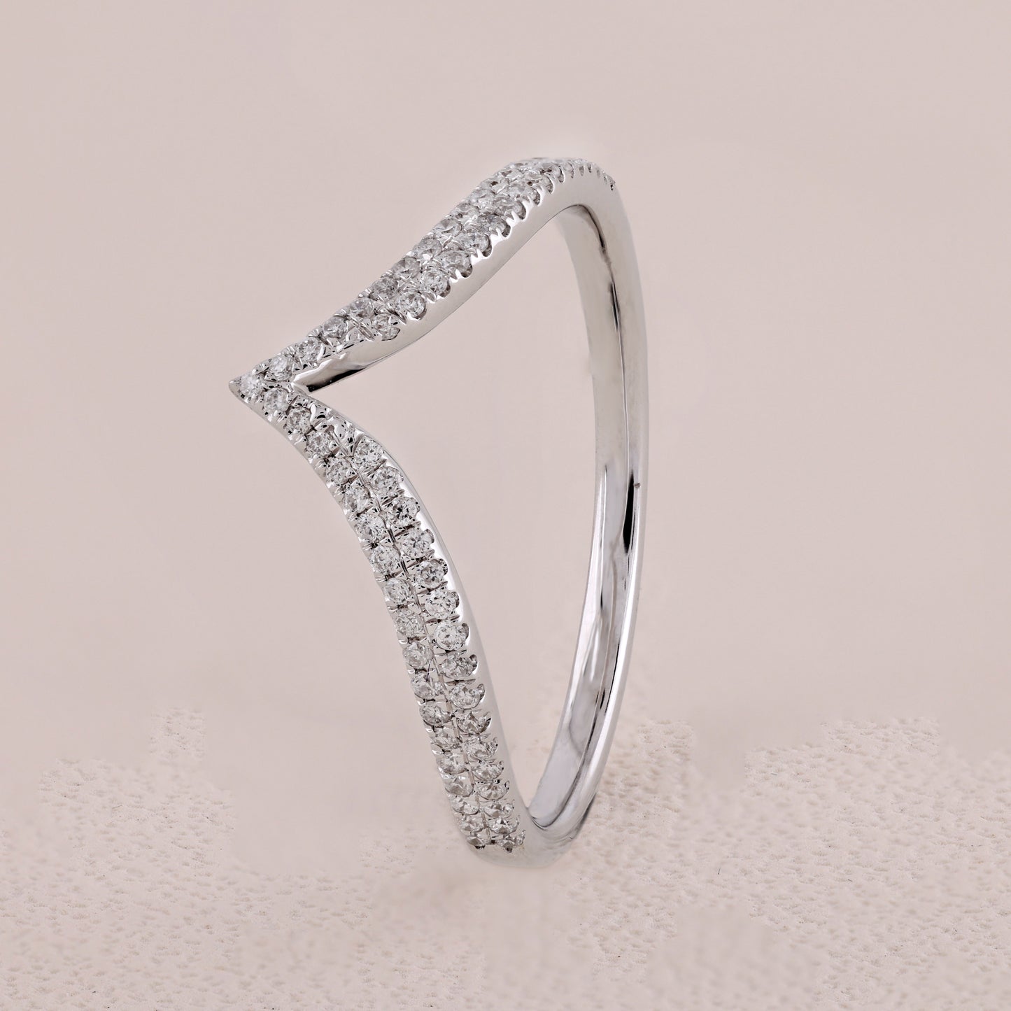 Silver ring with diamond accents on a beige background
