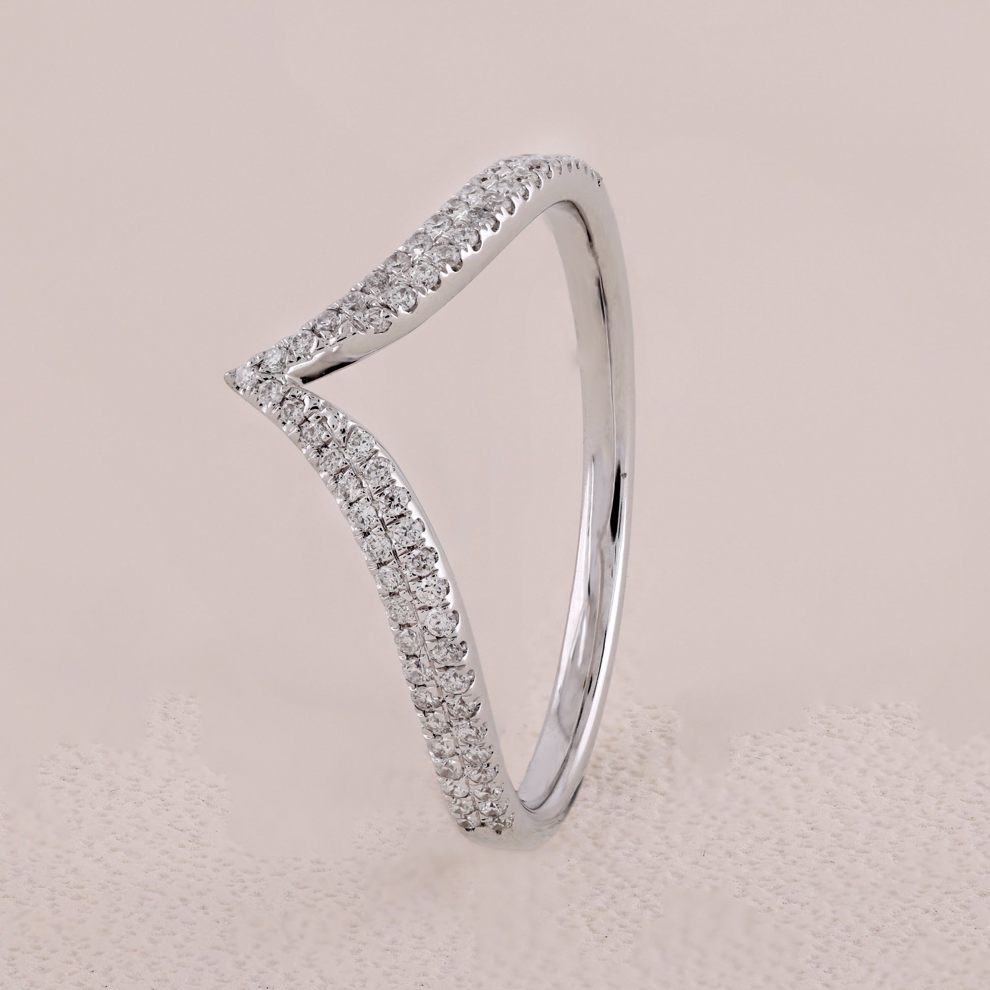 Silver ring with diamond accents on a beige background
