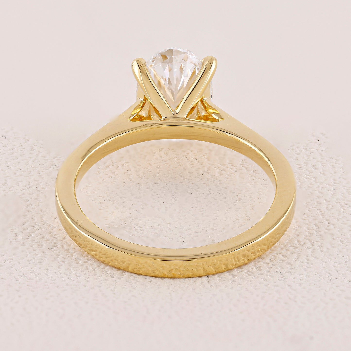 Gold ring with a clear gemstone on a textured beige background