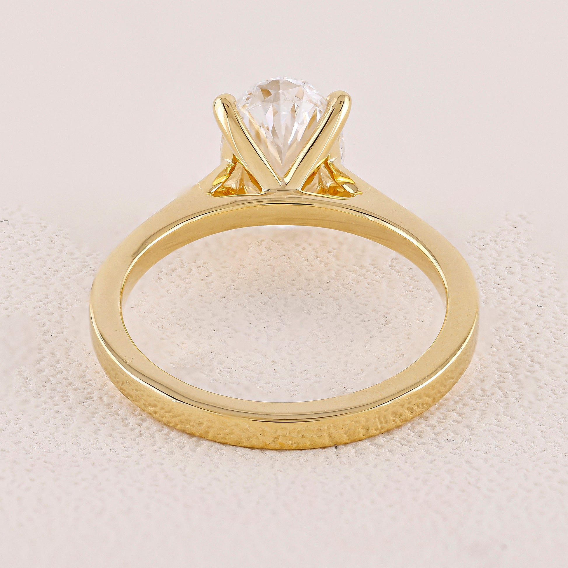 Gold ring with a clear gemstone on a textured beige background