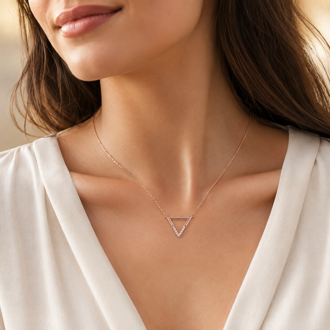 Close-up of a woman wearing a delicate gold necklace with a triangle pendant.