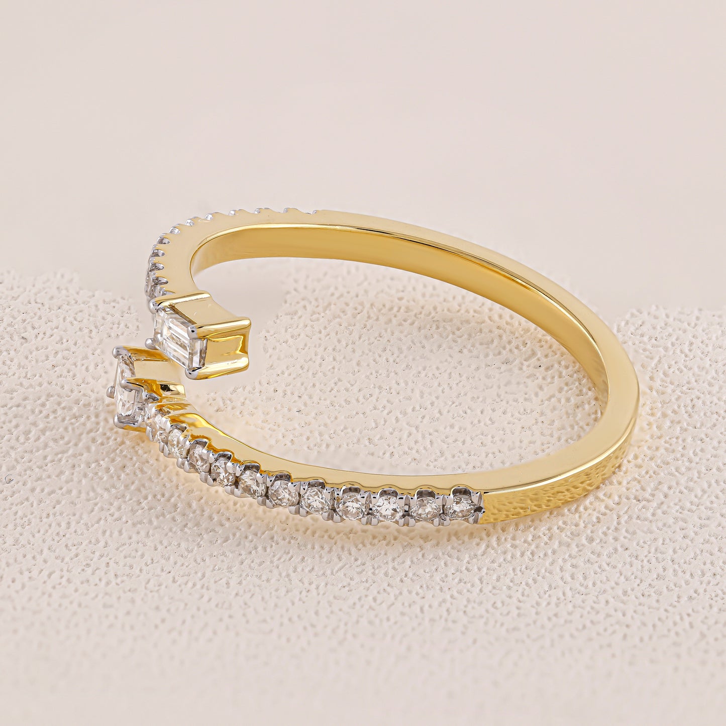 Gold ring with diamond accents on a light beige background