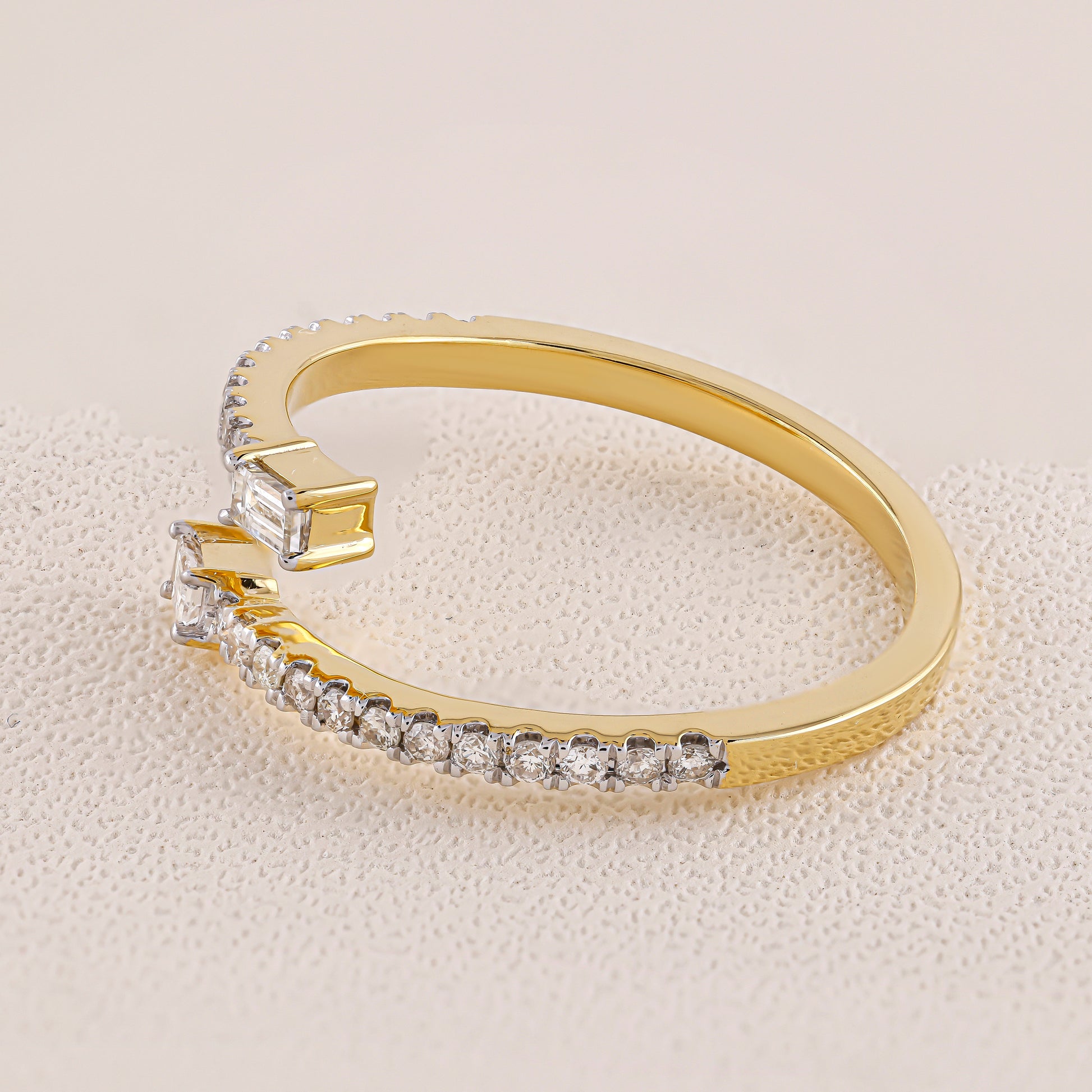 Gold ring with diamond accents on a light beige background