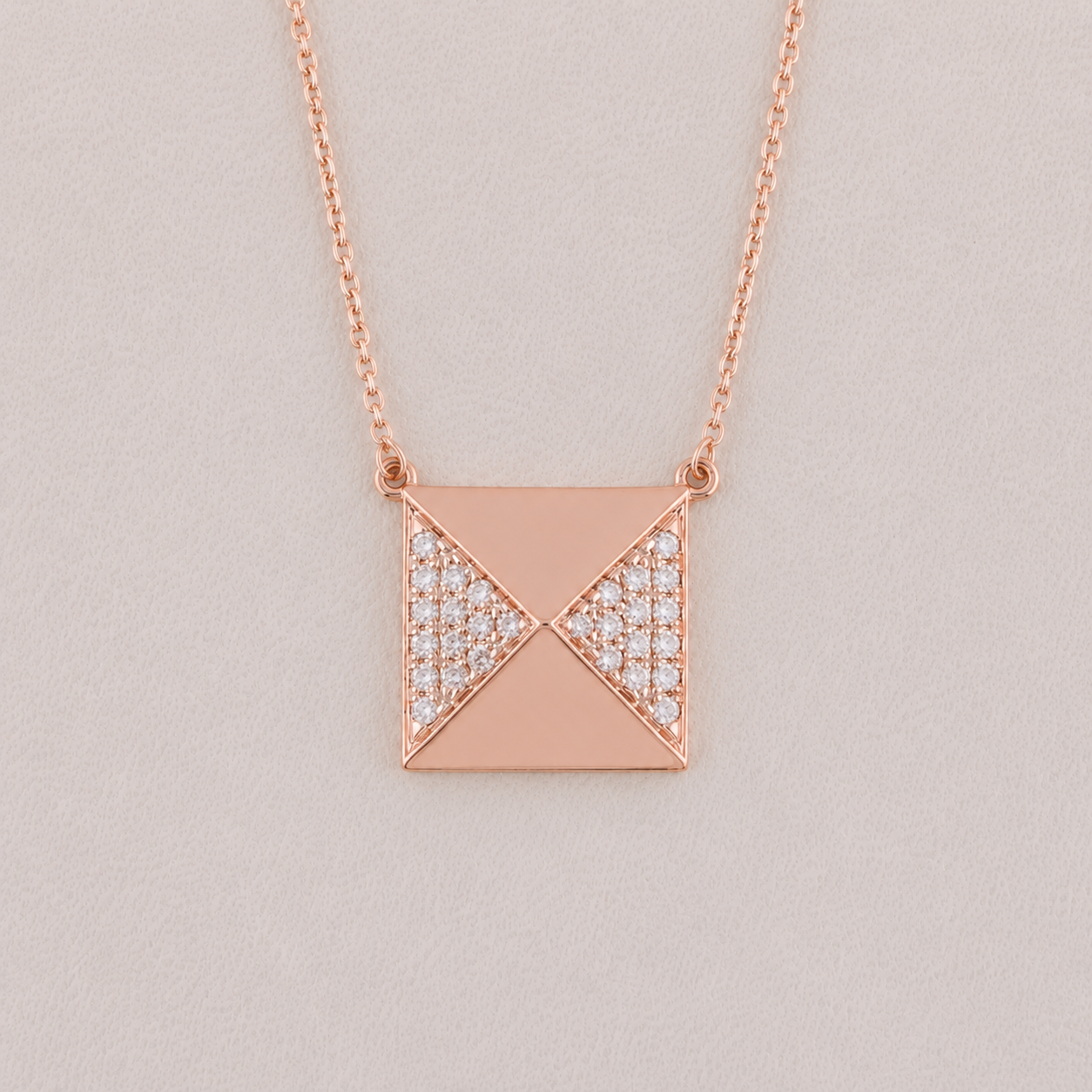 Rose gold necklace with a geometric pendant on a light gray background