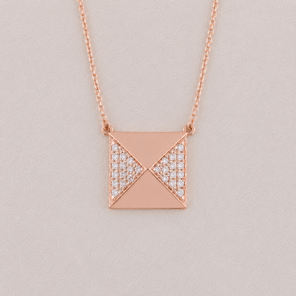 Rose gold necklace with a geometric pendant on a light gray background
