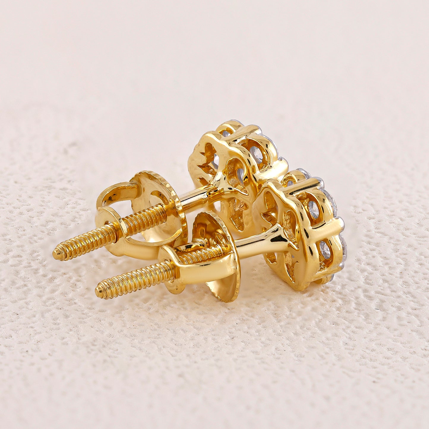 Gold screw-back earrings on a light beige fabric background