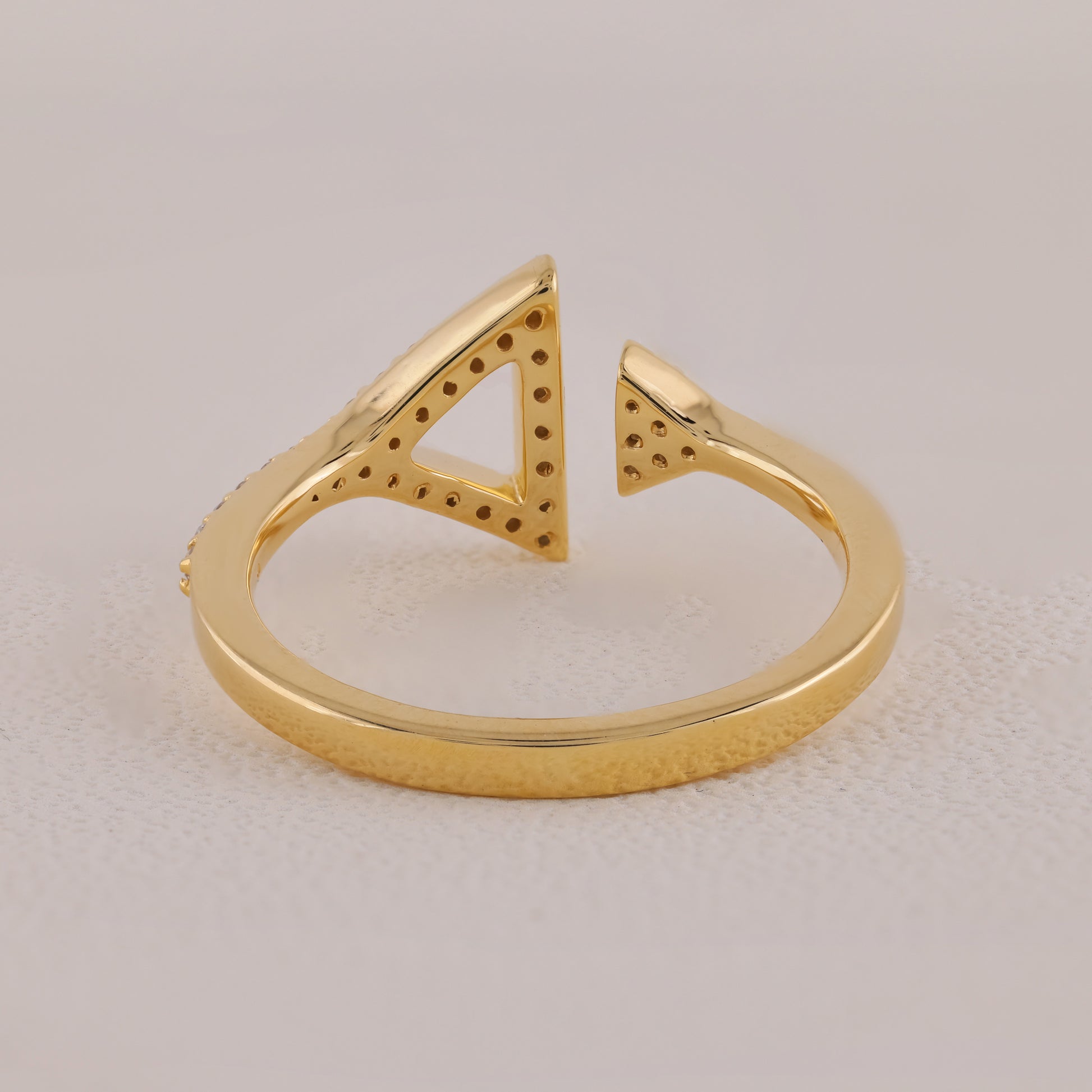 Gold open ring with geometric design on a light beige background
