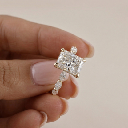 Gold ring with a large diamond held between fingers against a neutral background