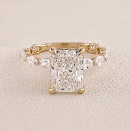 Gold ring with a large diamond and smaller diamonds on the sides on a beige fabric background
