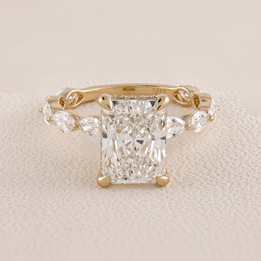 Gold ring with a large diamond and smaller diamonds on the sides on a beige fabric background