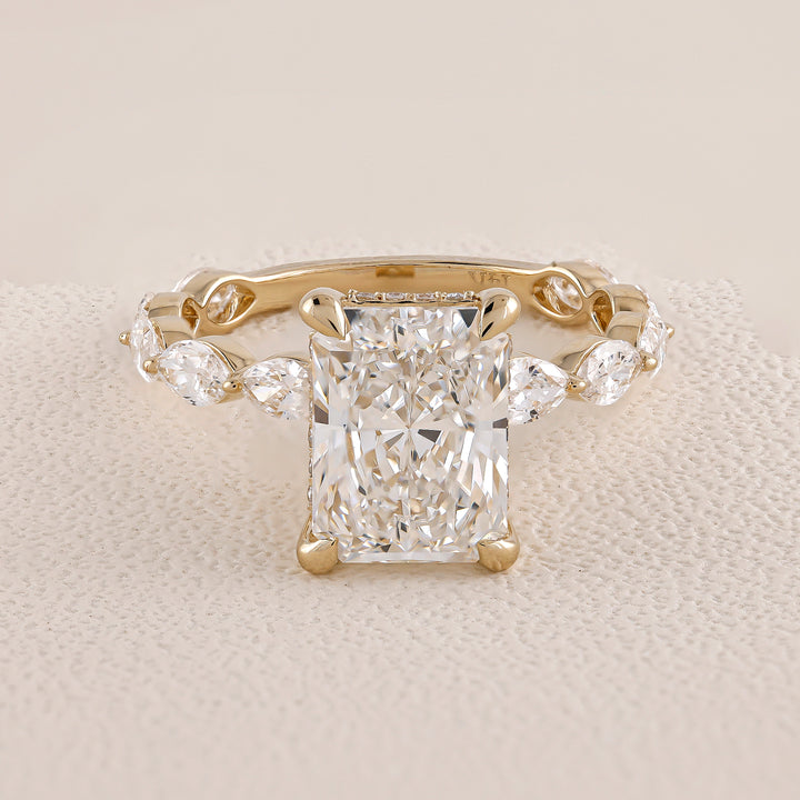 Gold ring with a large diamond and smaller diamonds on the sides on a beige fabric background