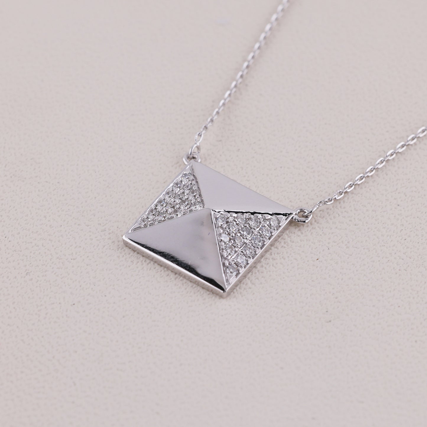 Silver necklace with a geometric pendant on a light gray background