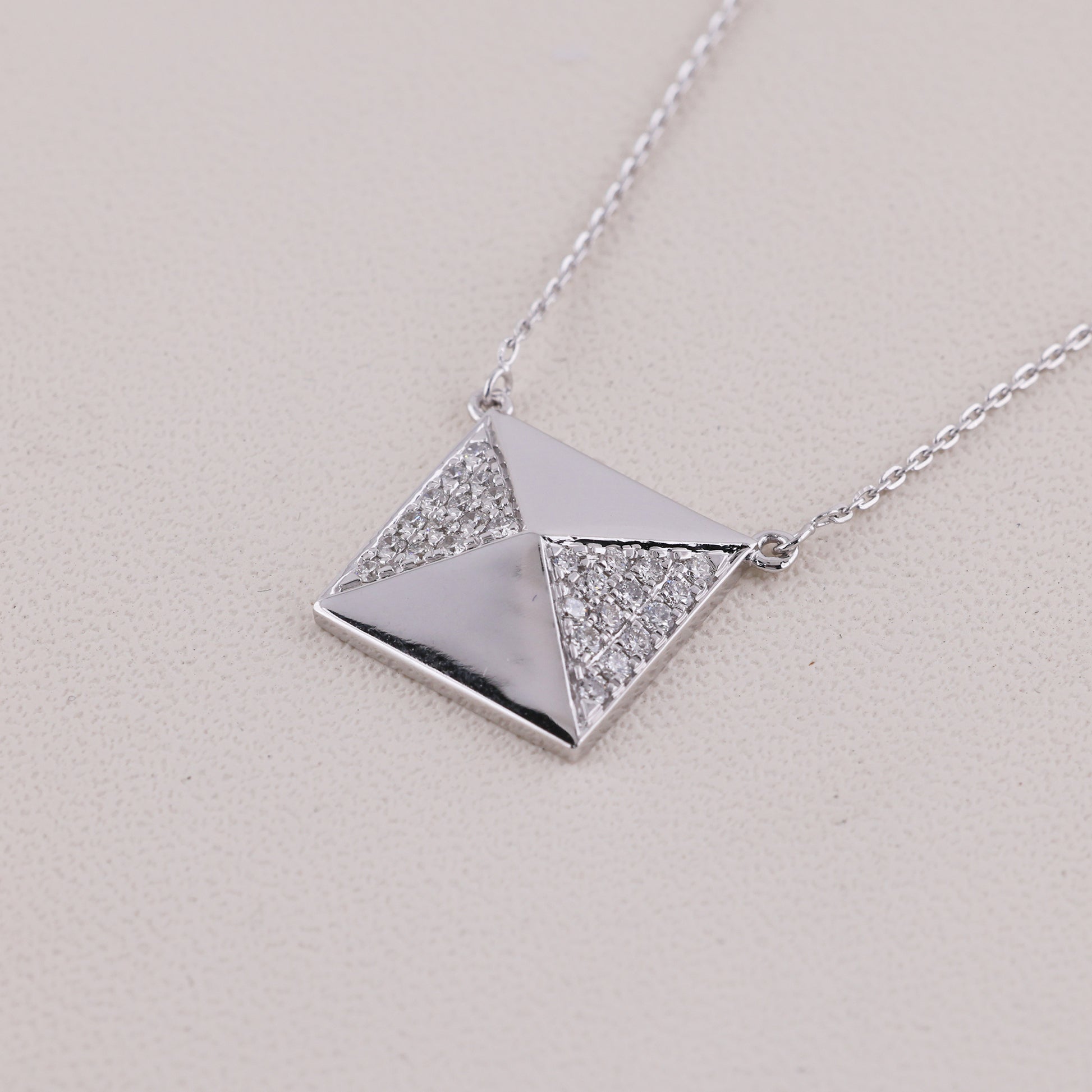 Silver necklace with a geometric pendant on a light gray background