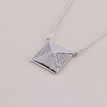 Silver necklace with a geometric pendant on a light gray background