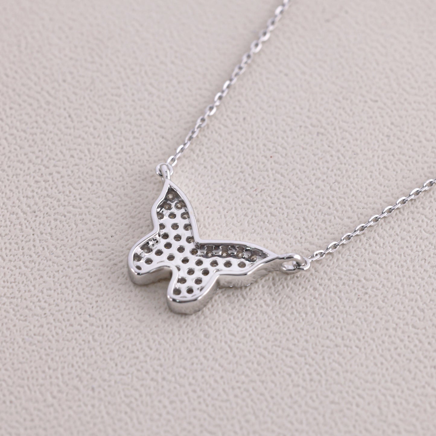 Silver butterfly necklace on a light gray background