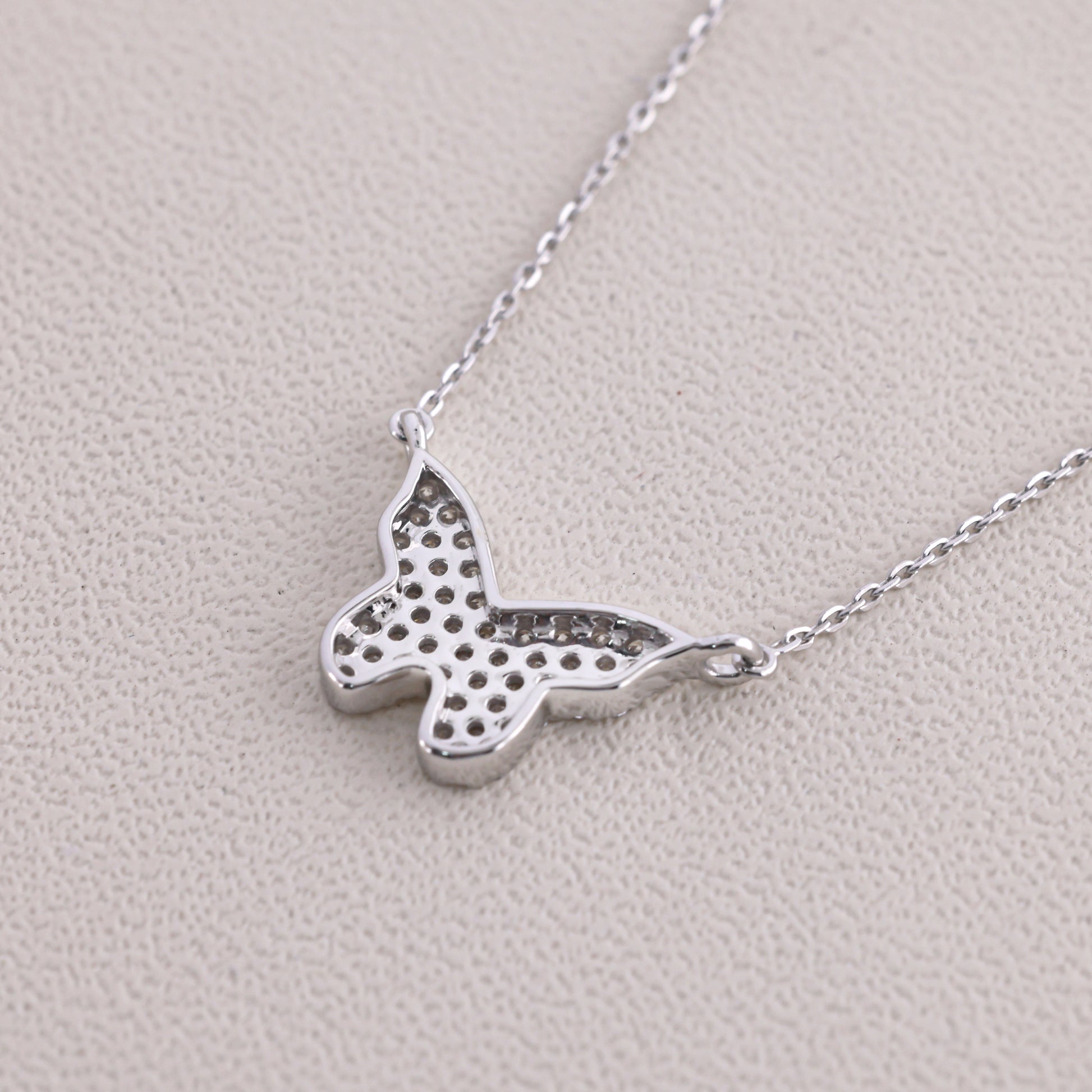 Silver butterfly necklace on a light gray background