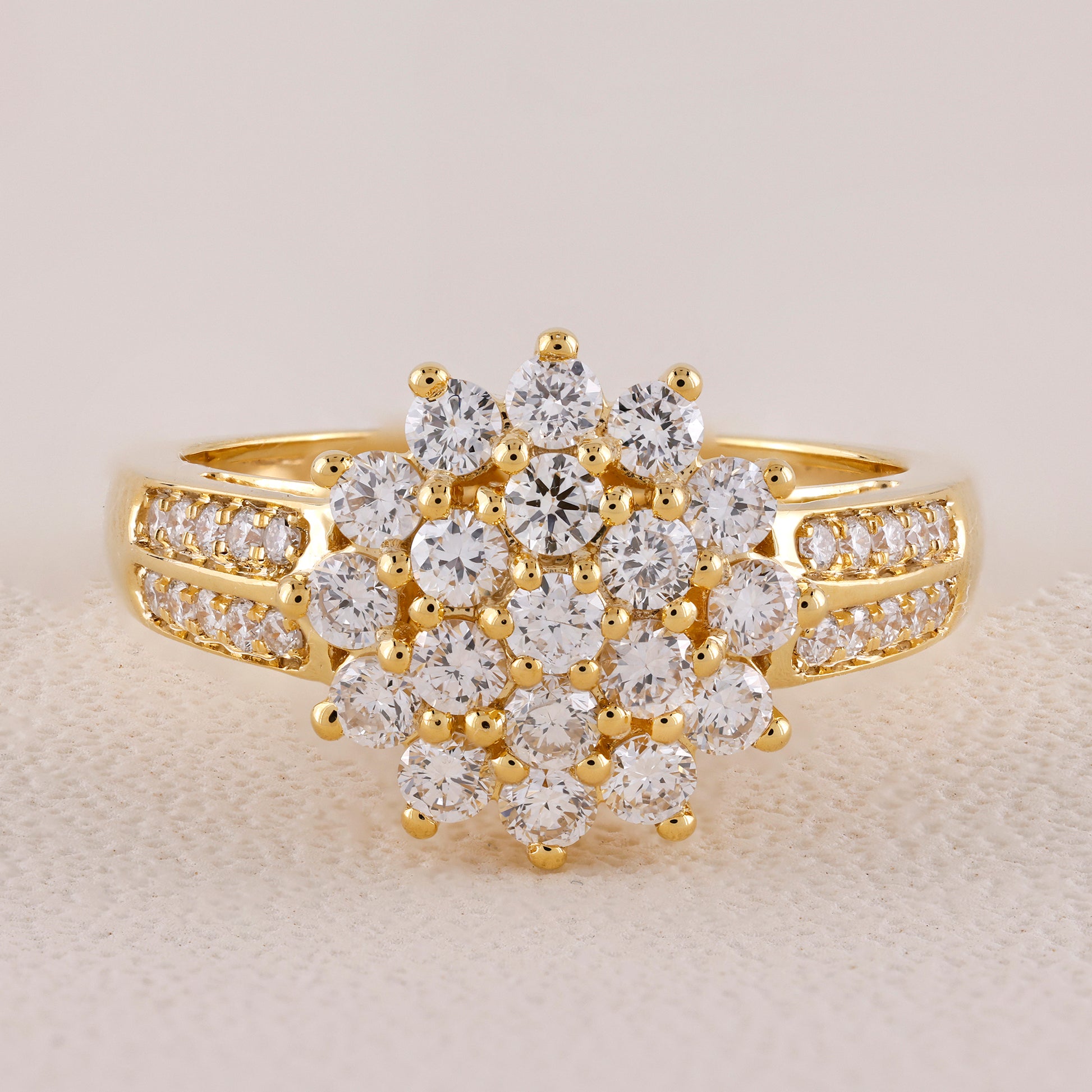 Gold ring with diamond cluster on a light background