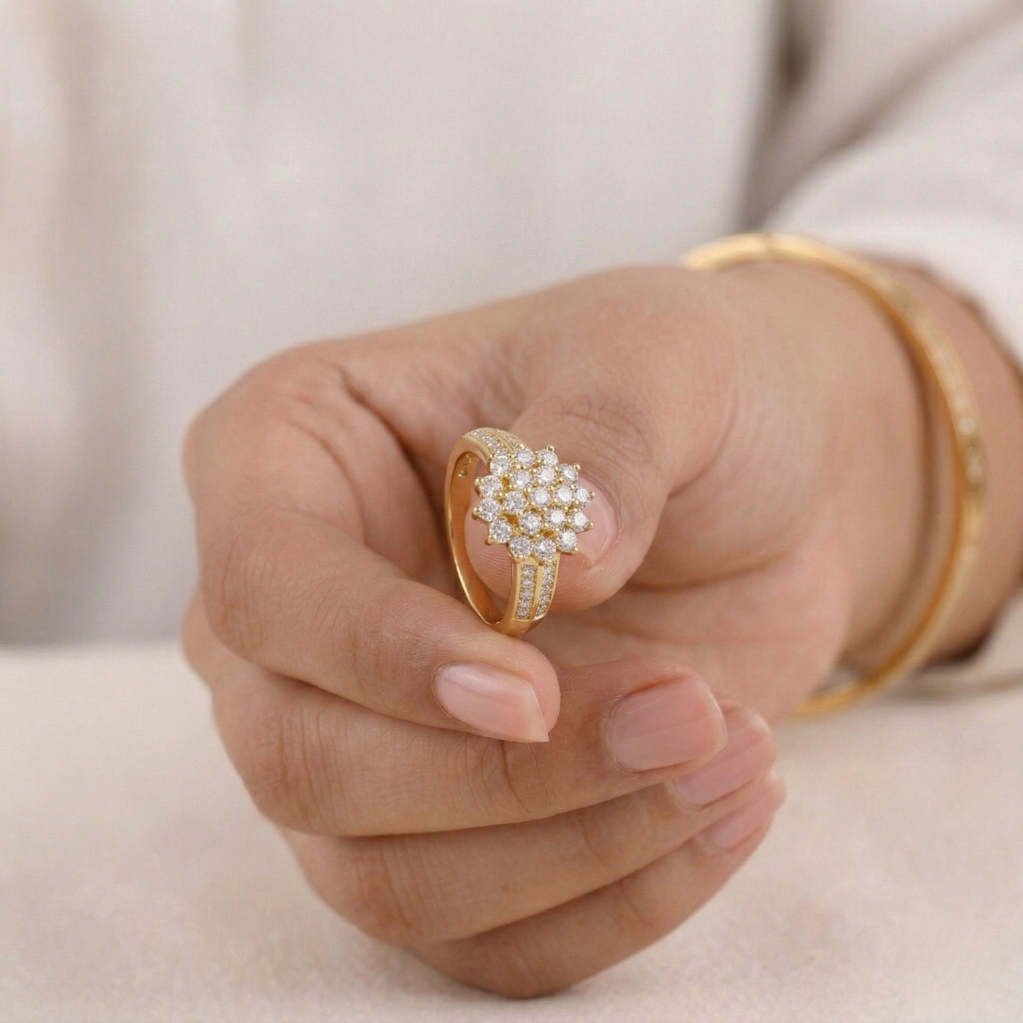 Gold ring with a floral design on a hand against a neutral background