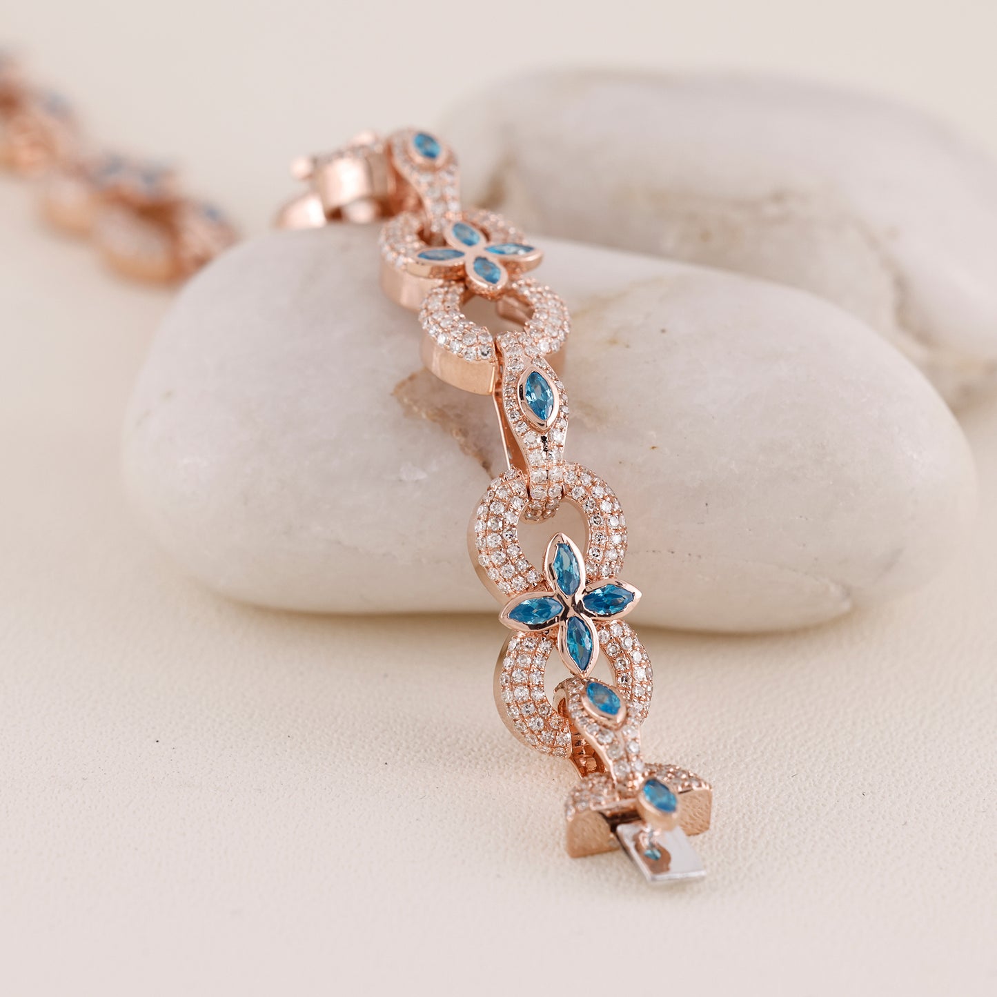 Rose gold bracelet with blue gemstones on a white stone surface
