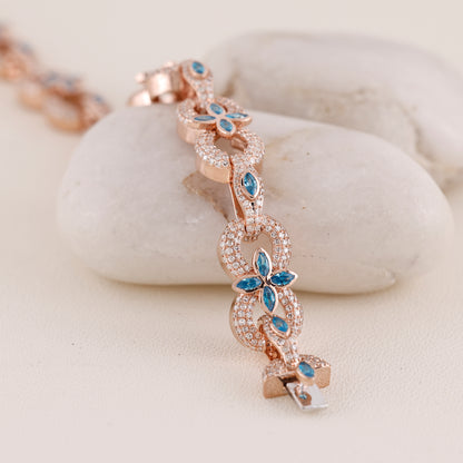Rose gold bracelet with blue gemstones on a white stone surface