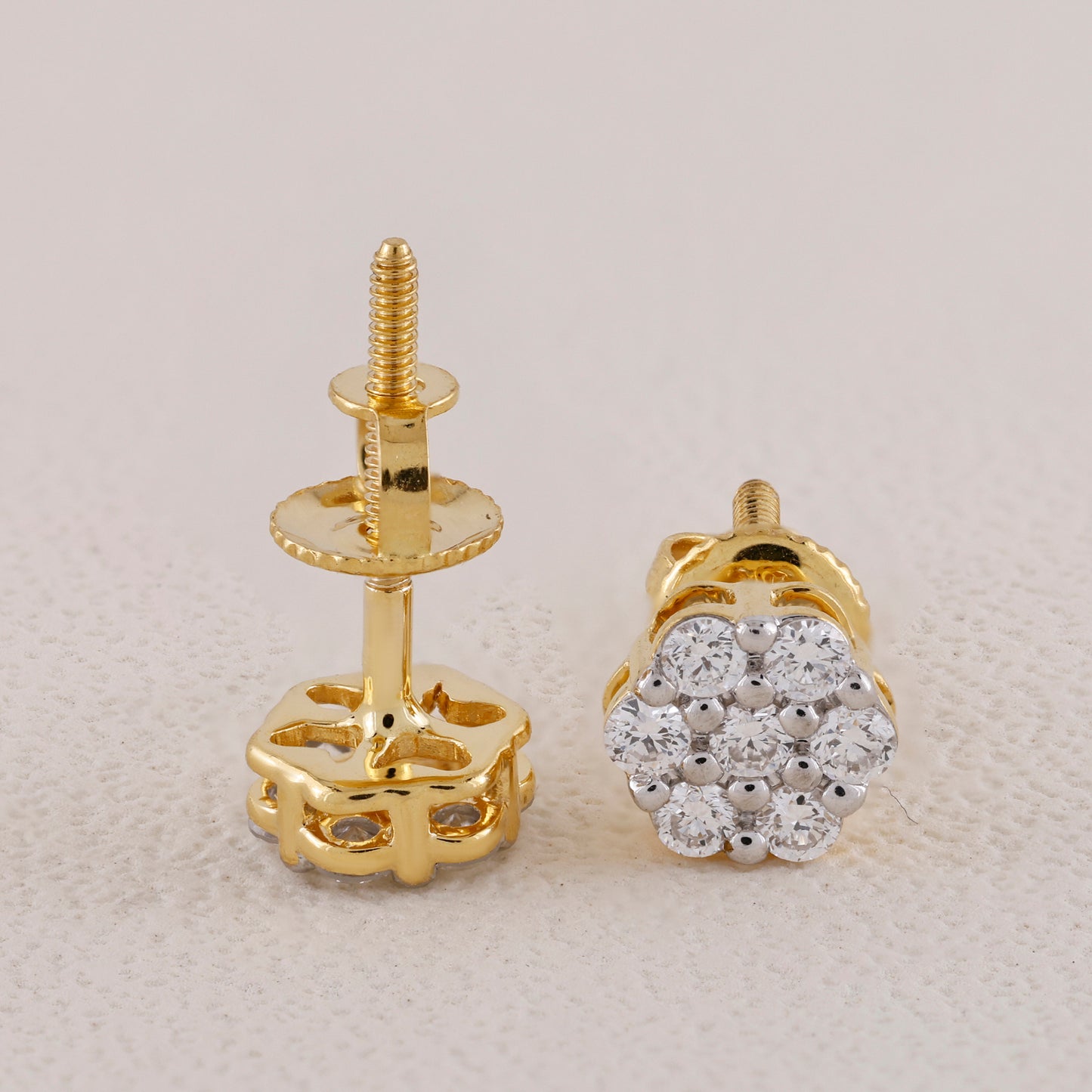Gold earring posts with a diamond-studded earring on a light gray background
