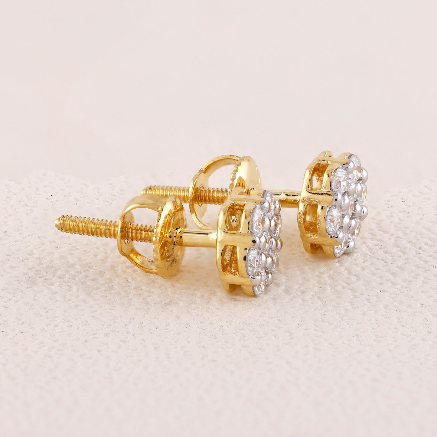 Gold earrings with a floral design on a light beige background