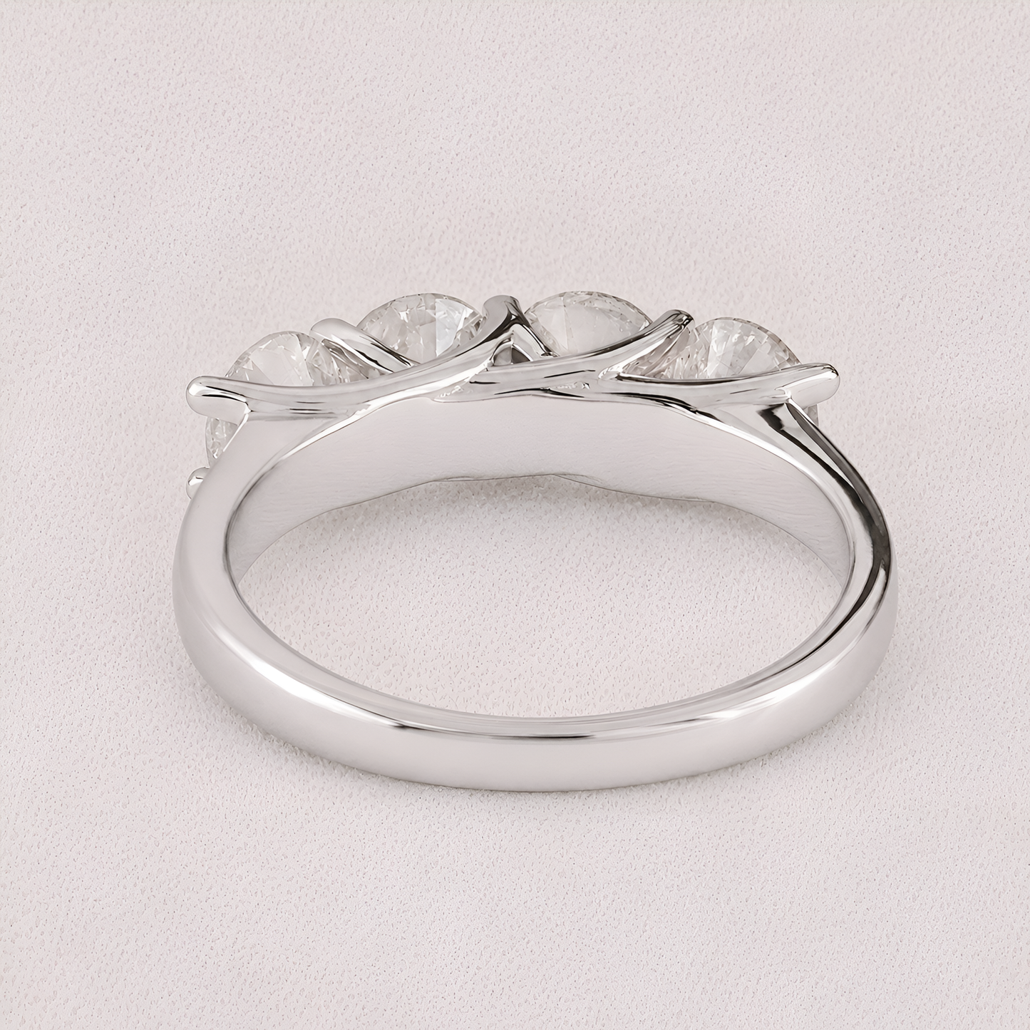 A silver-toned ring featuring a curved, branch-like setting with five clear, oval-cut gemstones, photographed on a light textured background.