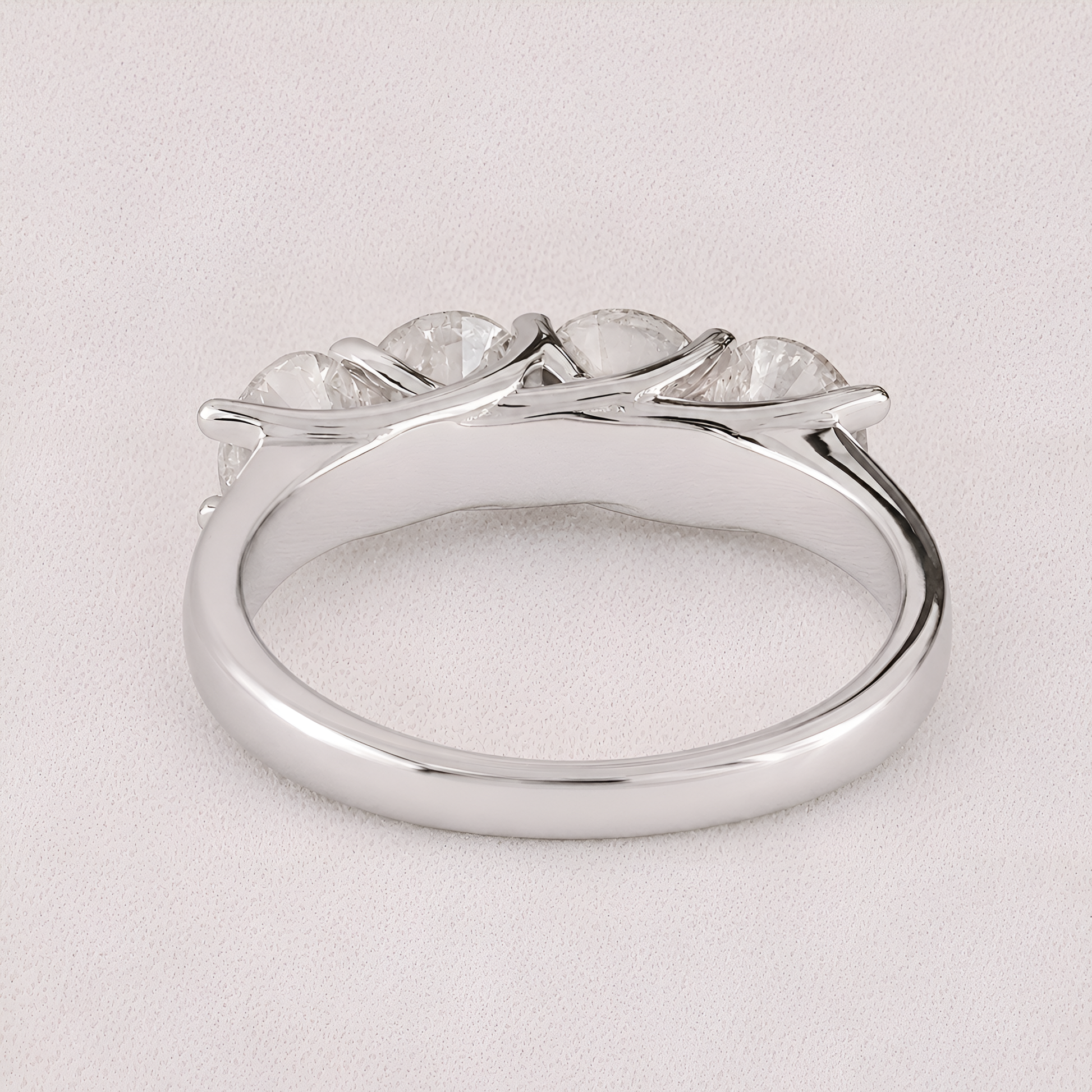 A silver-toned ring featuring a curved, branch-like setting with five clear, oval-cut gemstones, photographed on a light textured background.