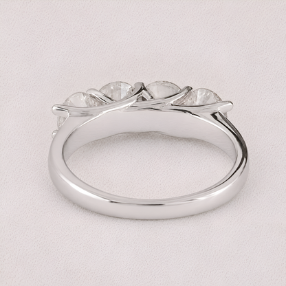 A silver-toned ring featuring a curved, branch-like setting with five clear, oval-cut gemstones, photographed on a light textured background.