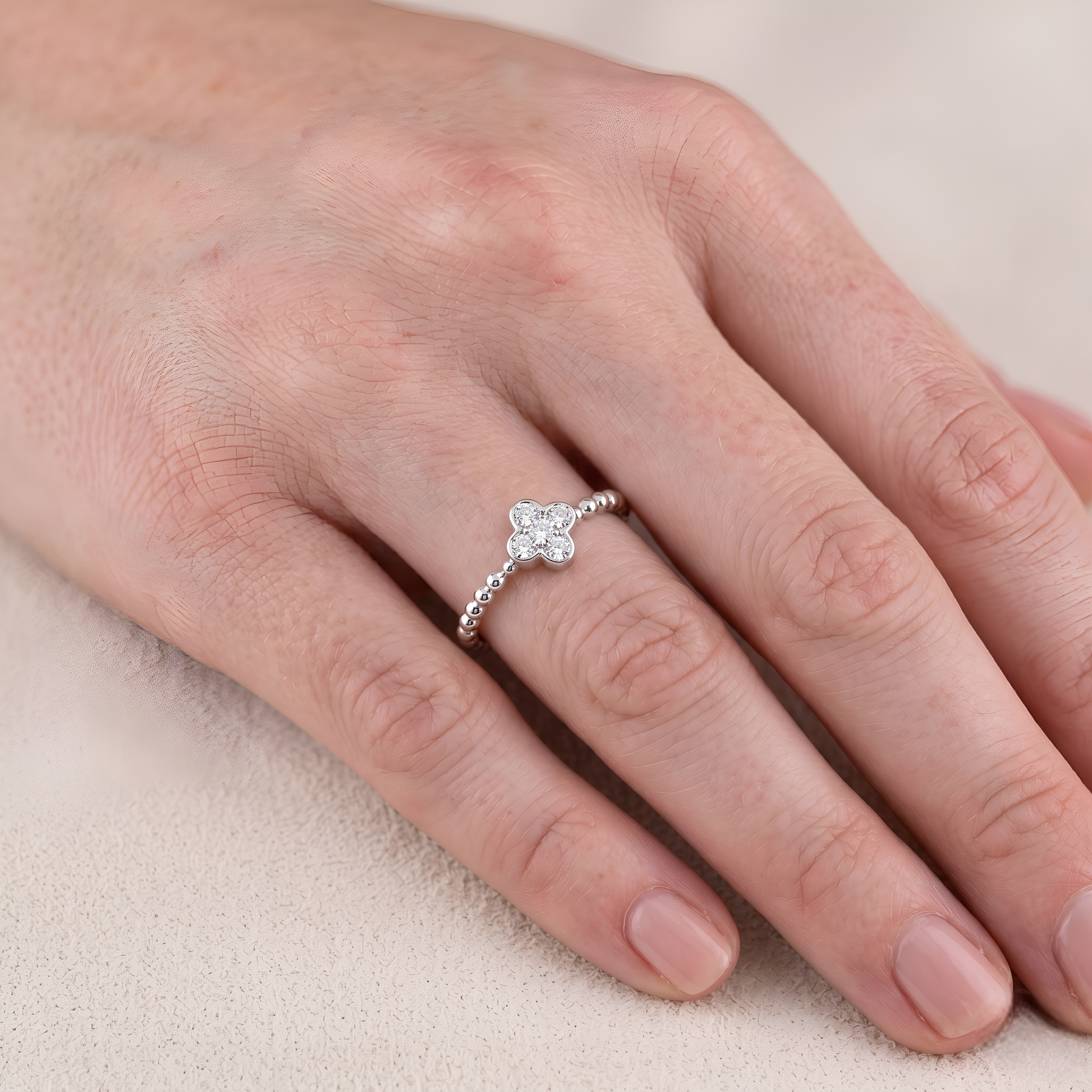 Hand wearing a diamond ring on a light background