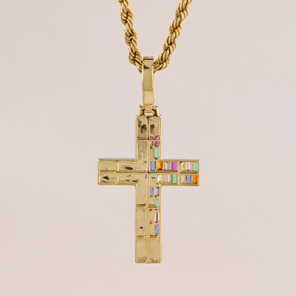 Gold cross pendant with colorful stones on a beige background