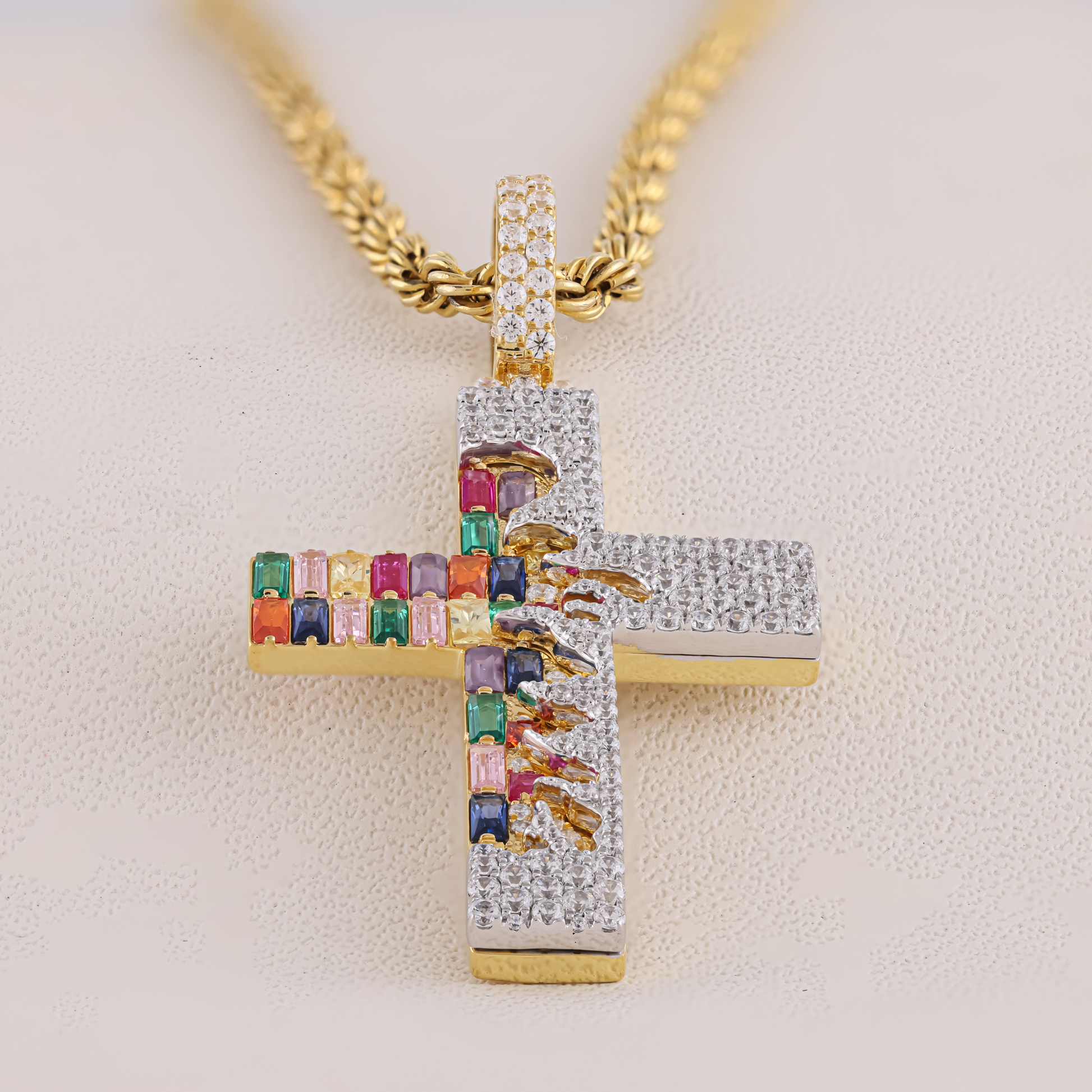 Gold cross pendant with colorful gemstones on a light background