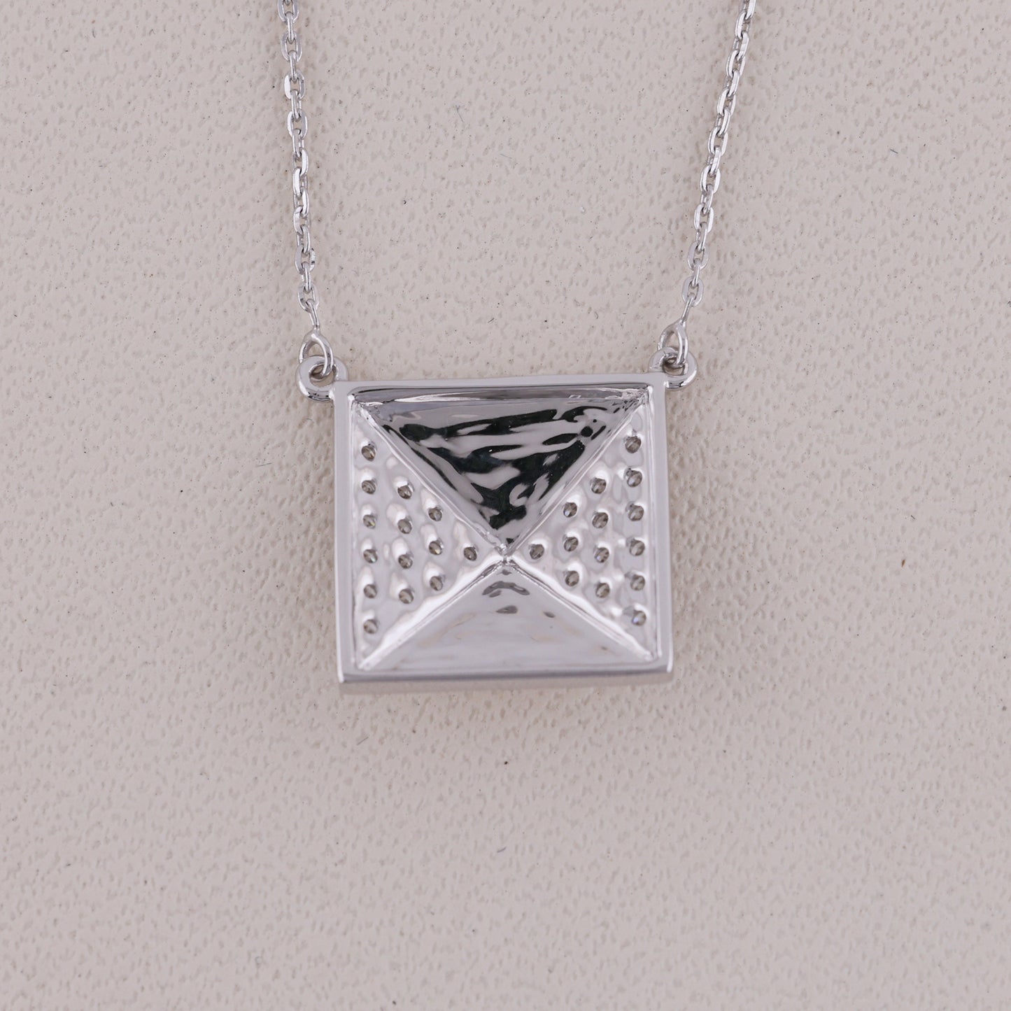 Silver geometric pendant necklace on a light gray background