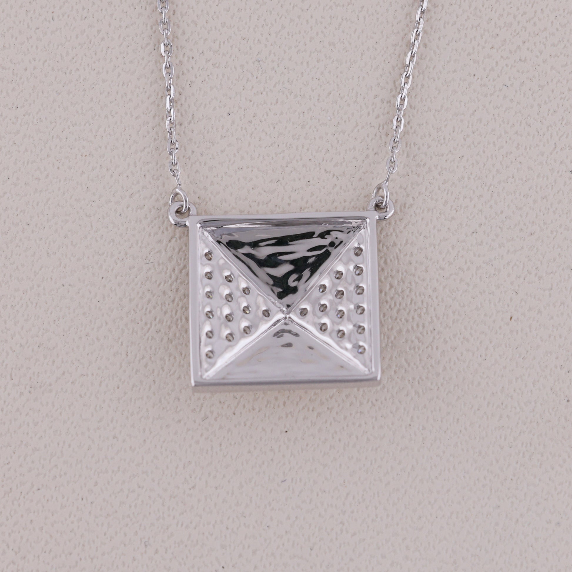 Silver geometric pendant necklace on a light gray background